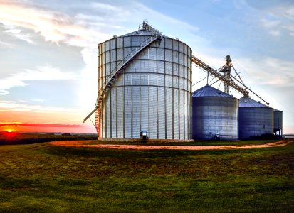 The set sets behind large, metal silos on a farm in Jackson County, Iowa. Original image from Carol M. Highsmith’s America, Library of Congress collection. photo