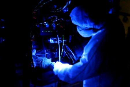 Using a black light, a technician closely inspects one of NASA's twin Radiation Belt Storm Probes inside the clean room high bay at Astrotech payload processing facility. photo