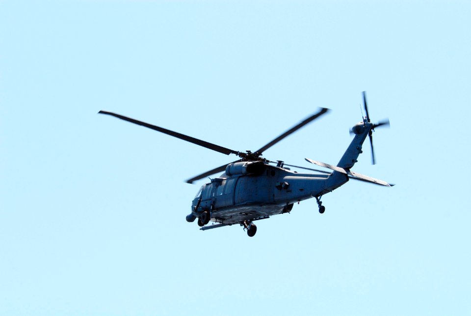 An HH-60G helicopter flies overhead of a rescue boat during a training exercise, known as Mode VIII.
