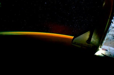 Earth’s thin line of atmosphere and a starry sky just off the port wing of the docked space shuttle Endeavour are featured in this image, 28 May 2011.