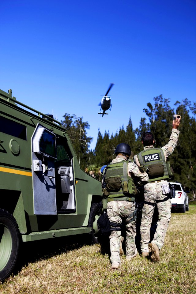 At NASA’s Protective Services Training Academy at Kennedy Space Center in Florida, a member of the Emergency Response Team, or tosses a flash bang diversionary device during a specialized training simulation as a helicopter hovers above.