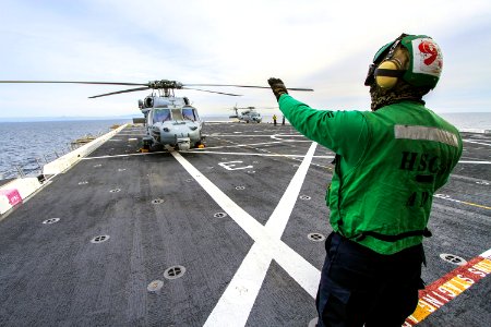 SAN DIEGO, Calif. – A member of the Helicopter Sea Combat Squadron 8 signals to the pilot in an H60-S Seahawk helicopter on the deck of the USS Anchorage as the ship departs Naval Base San Diego in California for the open waters of the Pacific Ocean. Dec 1st, 2014. photo