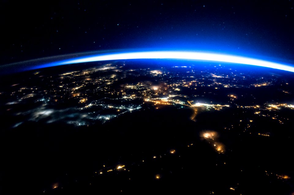 Night image of sparkling cities and a sliver of daylight framing the northern hemisphere.