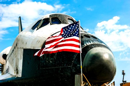 An American flag flaps proudly in the wind in front of space shuttle Atlantis on the Shuttle Landing Facility's Runway 15 at NASA's Kennedy Space Center in Florida. photo