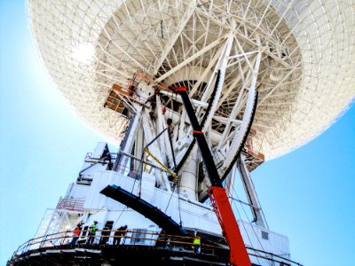 Under the unflinching summer sun, workers at NASA's Deep Space Network complex in Goldstone, Calif., use a crane to lift a runner segment that is part of major surgery on a giant, 70-meter-wide antenna. photo