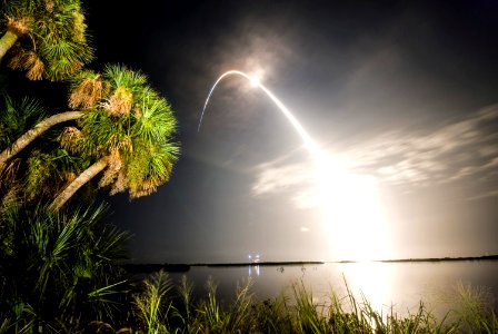 Viewed from the Banana River Viewing Site at NASA's Kennedy Space Center in Florida, space shuttle Discovery arcs through a cloud-brushed sky lighted by the trail of fire after launch on the STS-128 mission. photo