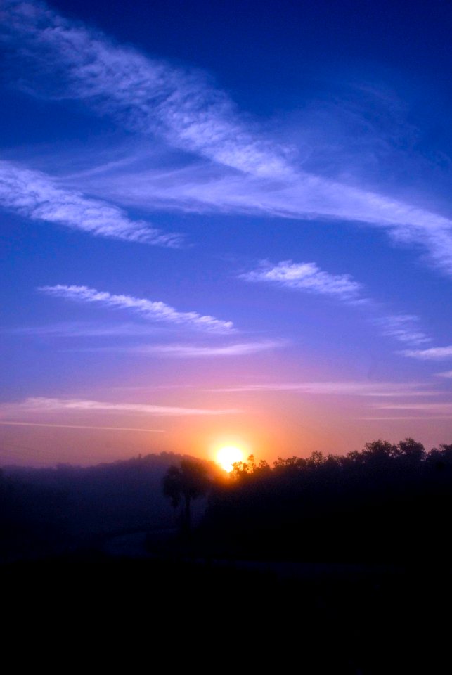 Sunrise casts an orange glow over the wooded landscape surrounding NASA's Kennedy Space Center.