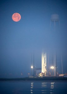 The full Moon sets in the fog behind the Orbital Sciences Corporation Antares rocket.