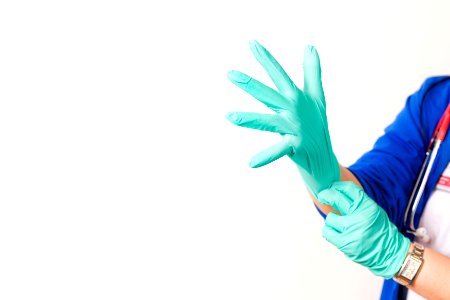 Nurse wearing green latex gloves to protect herself. Original image sourced from US Government department: Public Health Image Library, Centers for Disease Control and Prevention. Under US law this image is copyright free, please credit the government department whenever you can”.