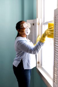 Woman using a damp sponge to clean dust collected on a window sill. Original image sourced from US Government department: Public Health Image Library, Centers for Disease Control and Prevention. Under US law this image is copyright free, please credit the government department whenever you can”. photo