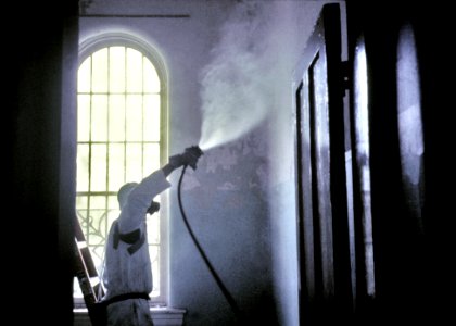 A worker wearing a protective mask and suit. Original image sourced from US Government department: Public Health Image Library, Centers for Disease Control and Prevention. Under US law this image is copyright free, please credit the government department whenever you can”.