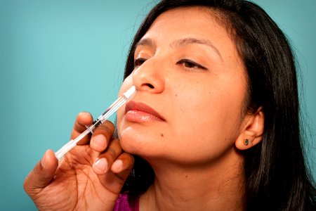 A healthcare practitioner administering the H1N1 live attenuated intranasal vaccine (LAIV) to a female recipient. Original image sourced from US Government department: Public Health Image Library, Centers for Disease Control and Prevention. Under US law this image is copyright free, please credit the government department whenever you can”.