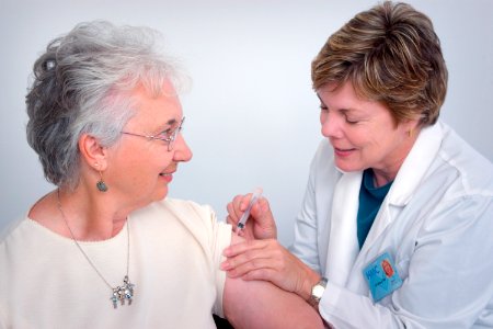 A doctor administering an intramuscular immunization to a middle–aged woman. Original image sourced from US Government department: Public Health Image Library, Centers for Disease Control and Prevention. Under US law this image is copyright free, please credit the government department whenever you can”. photo