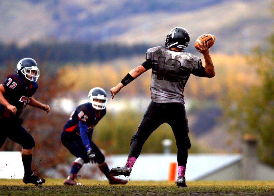 2 Football Player Running After Person Holding Football During Daytime In Shallow Focus Photography
