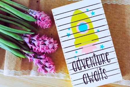 Adventure Awaits Art Work Beside Purple Flowers