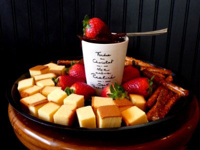 White Ceramic Mug On Top Sppon And Strawberry Surrounded Leche Plan And Strawberry On Black Round Shape Tray photo