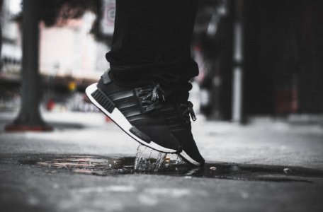 Grayscale Photo Of Person Wearing Adidas Nmd Jumping On Puddle photo
