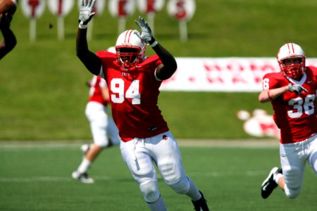 Person Wearing Nfl Suit With A Man Wearing White And Red Nfl Suit Running On Green Grass Field photo