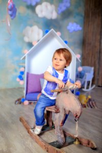 Boy In Blue And White Crew Neck T Shirt Riding On Wooden Rocking Moose photo