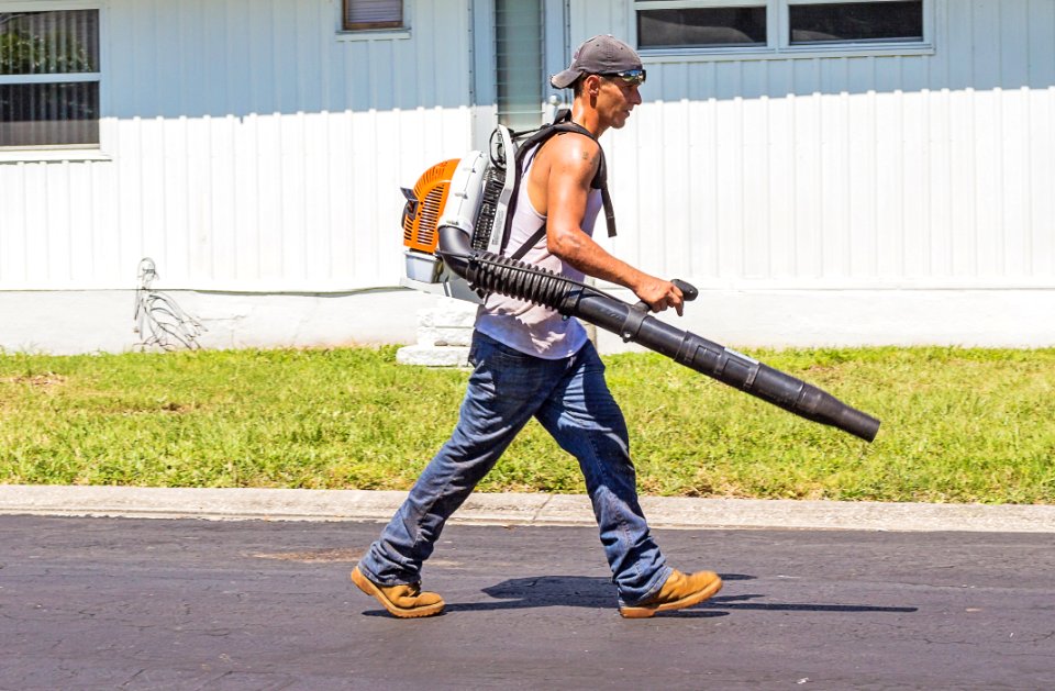 Man In White Tank Top And Blue Denim Pants With Leaf Blower Outdoors During Daytime
