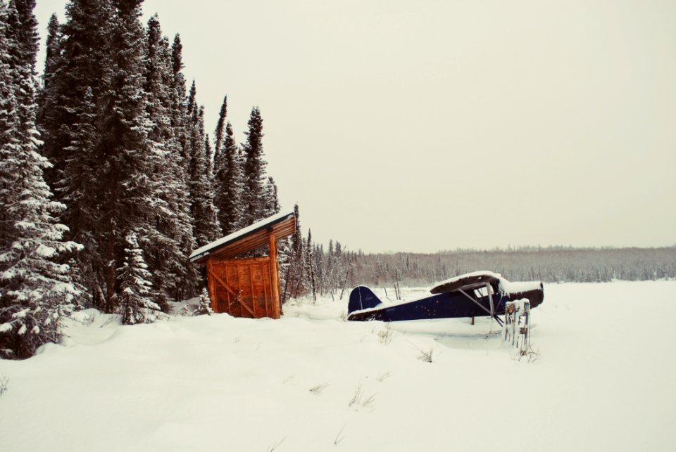 Black Aircraft Beside Brown Bunk House On Snowy Place