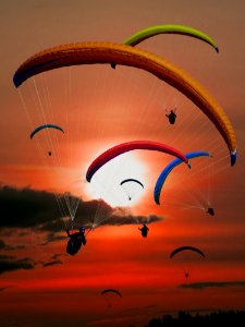 People Riding Parachutes During Sunset