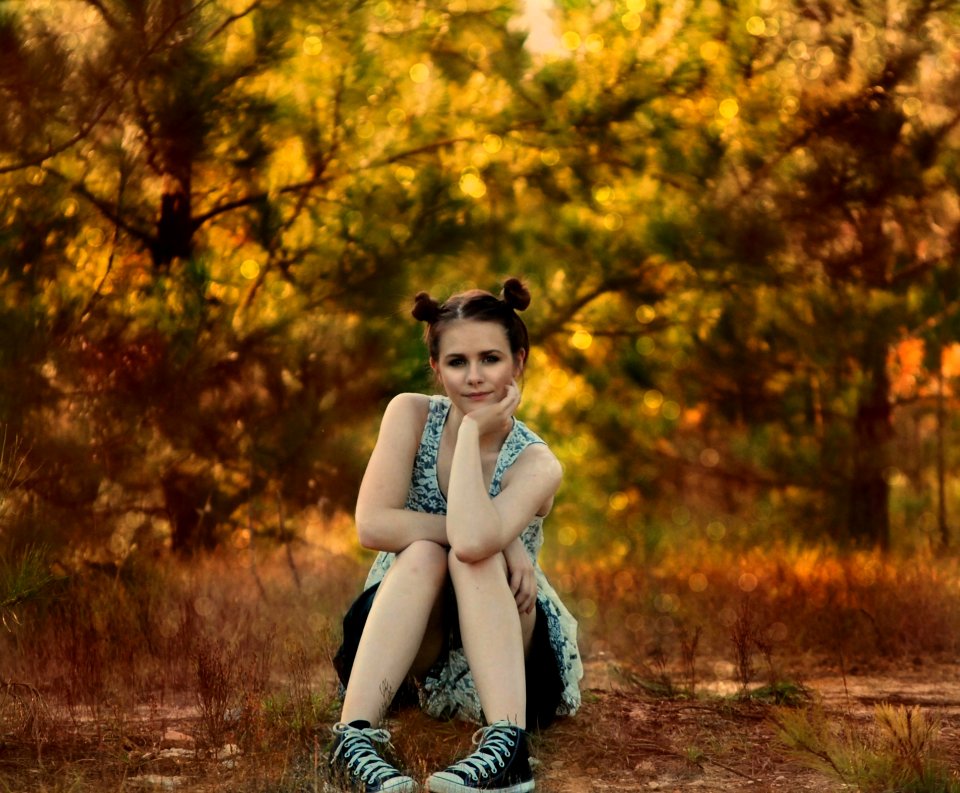 Young Woman Sitting Beside Trees In Autumn