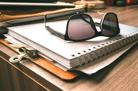 Black Frame Wayfarer Sunglasses On White Notebook photo