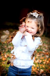 Focus Photo Of Girl In White Long Sleeve Shirt With Brown Leaf On Her Head photo