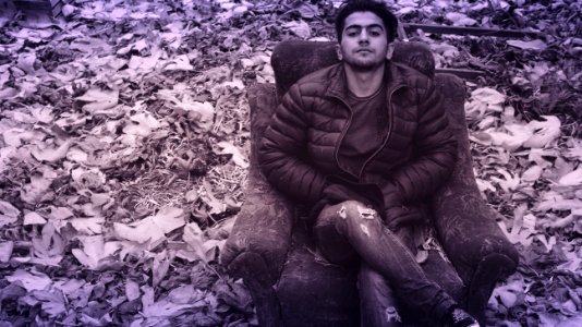 Man In Black Puffer Jacket And Distress Jeans Sitting In Couch