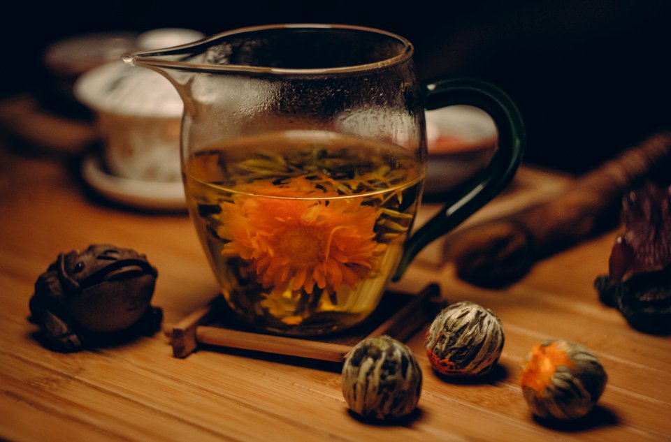 Orange Petaled Flowers In Clear Glass Pitcher With Water On Brown Table Close Up Photography