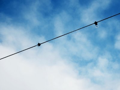 Electric Cable With Light Bulb Under Bright Sky
