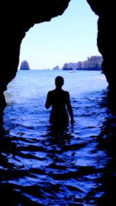 Silhouette Of Woman At Blue Sea Inside Black Cave During Daytime