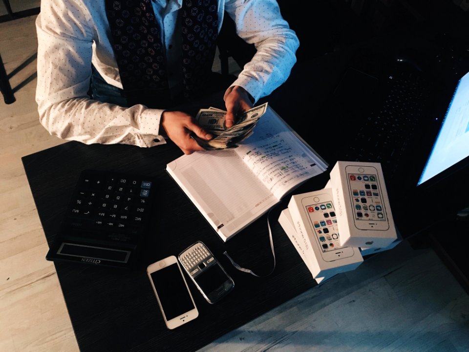 Person Counting Money With Smartphones In Front On Desk photo