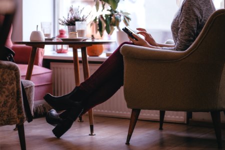 Woman Wearing Heather Gray Long Sleeve Top Red Fitted Pants And Chunky Boots Sitting On Sofa photo