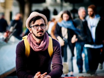 Man Sitting Next To Couple Of Person Walking On The Street During Daytime