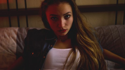 Woman In Blue Denim And White Shirt Sitting Inside Brown Painted Room photo