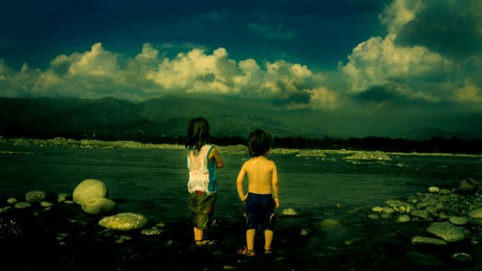 Child In White Tank Top Beside Child In Black Shorts Near Sea During Daytime