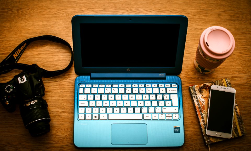Blue Hp Netbook Beside Black Nikon Dslr Camera And White Samsung Smartphone On Book