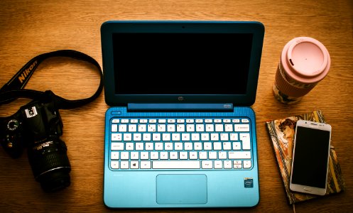 Blue Hp Netbook Beside Black Nikon Dslr Camera And White Samsung Smartphone On Book photo