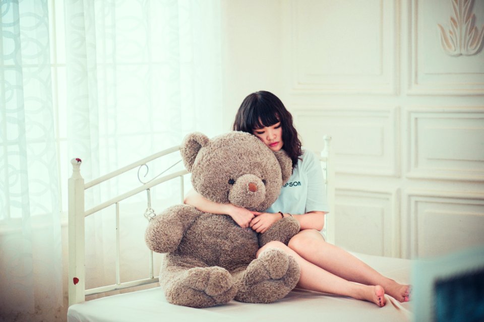 Woman Hugging Teddy Bear On Bed