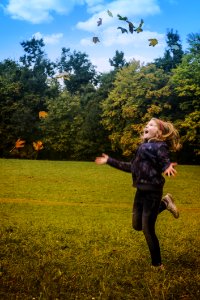 Girl In Black Jacket Standing On Green Grass During Daytime photo