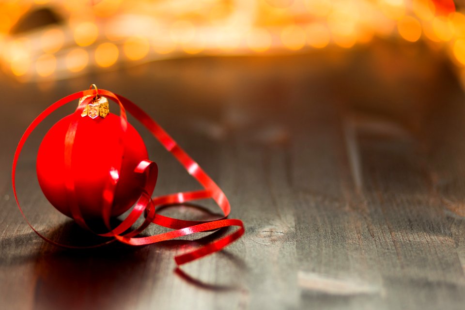 Red Christmas Bauble With Red Ribbon On Wooden Surface In Close Up Photography