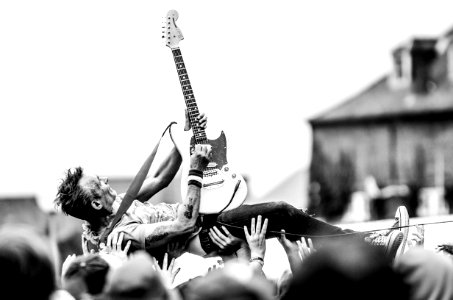 Gray Scale Photo Of Man Lifted By People Holding Stratocaster Guitar photo