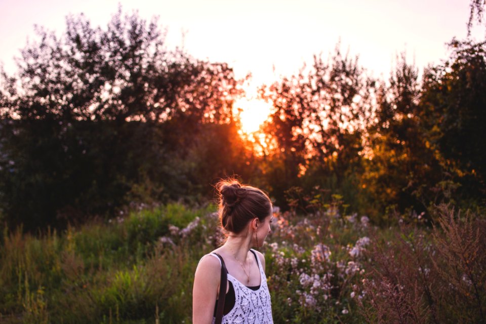 Selective Focus Photography Of Woman Standing In The Middle Of Grasses And Flowers During Golden Hour