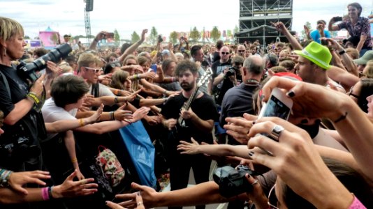 Man In Black Crew Neck T Shirt And Pants Playing Guitar Surrounded By Crowd photo