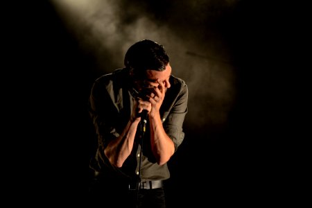 Man In Gray Dress Shirt Holding Mic In Dark Room