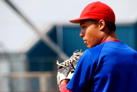 Man In Red Fitted Cap Wearing Blue Shirt With White Leather Baseball Mitt On Hand During Daytime photo