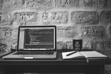 Grayscale Photo Of Computer Laptop Near White Notebook And Ceramic Mug On Table photo