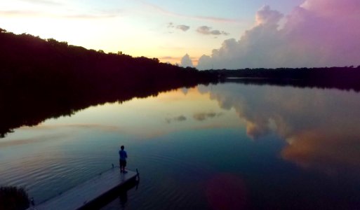 Man Standing On River Dock During Sunset